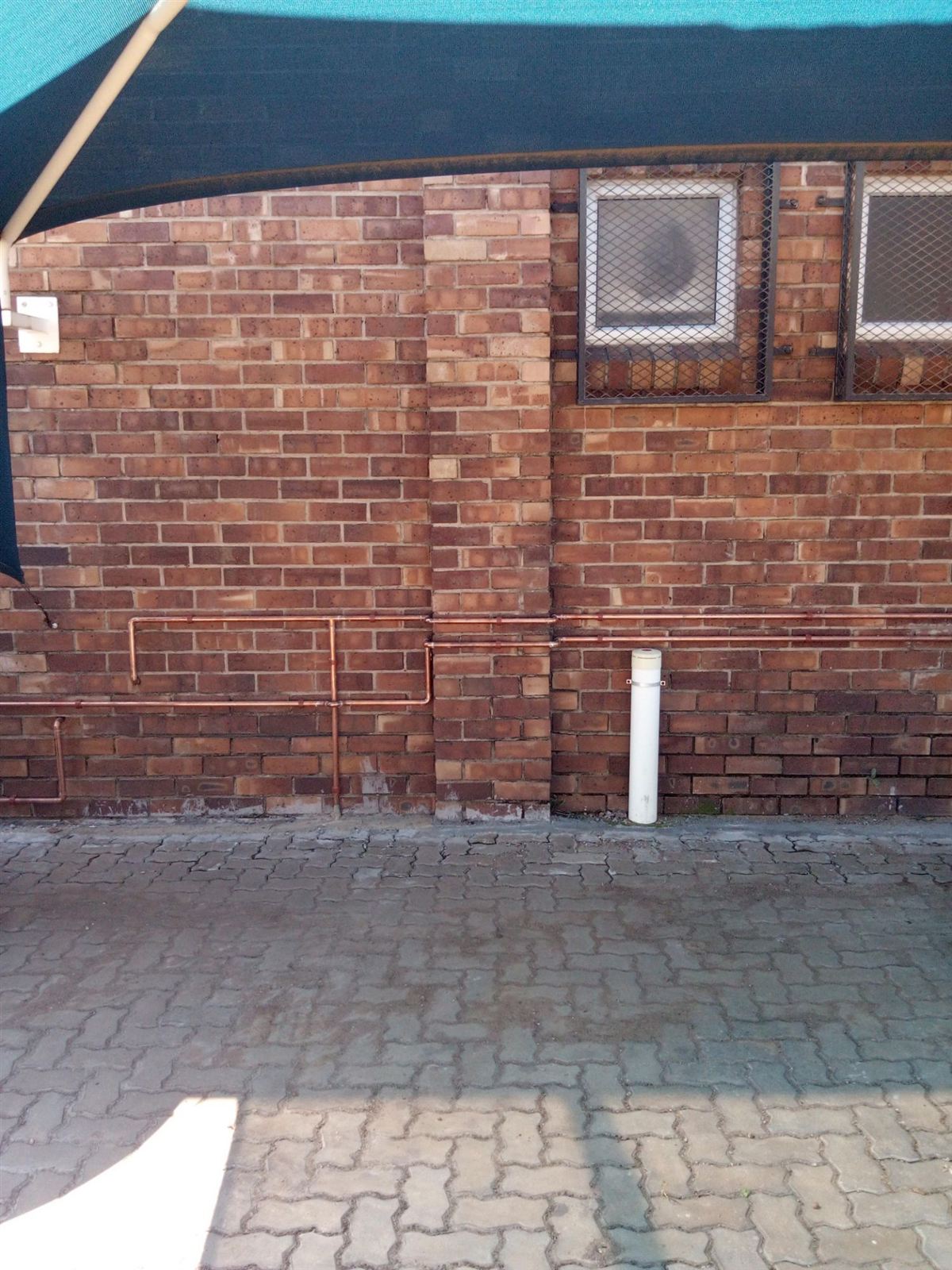 Neat copper water lines along a brick wall