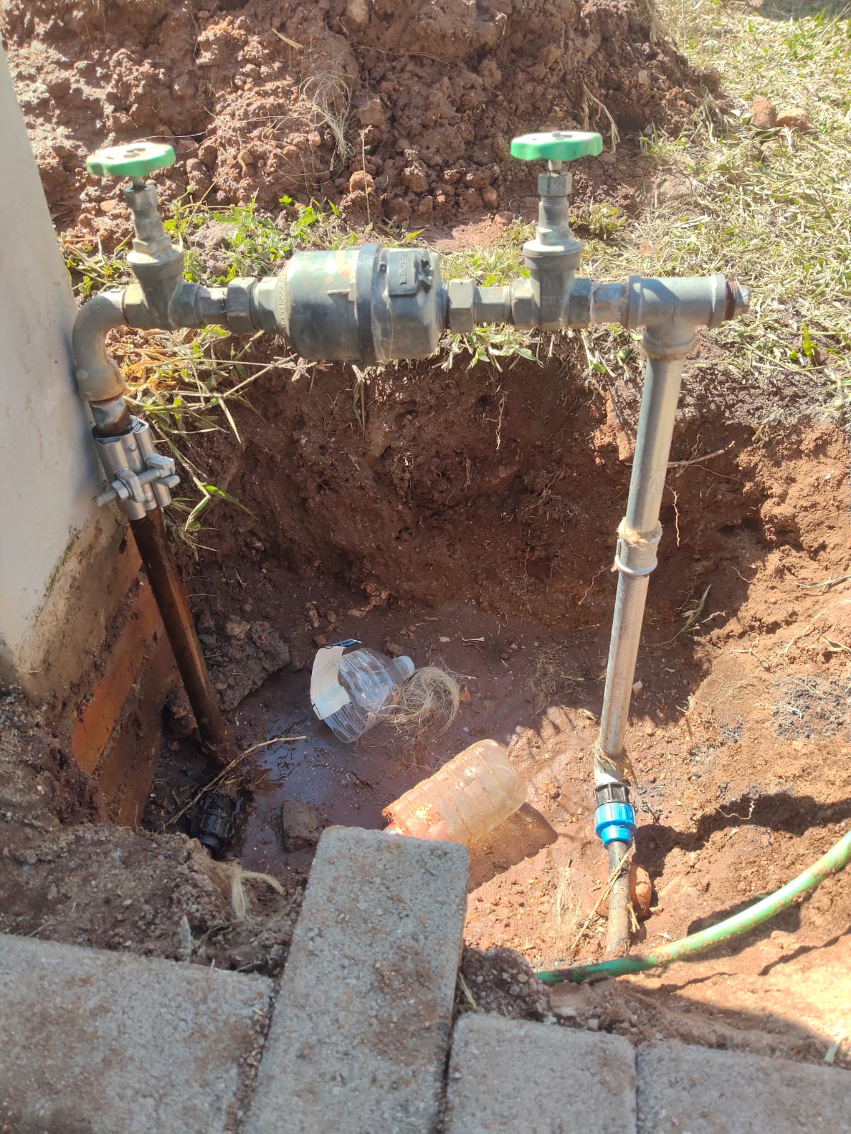 Water meter and valves in an excavated hole with new pipe fittings