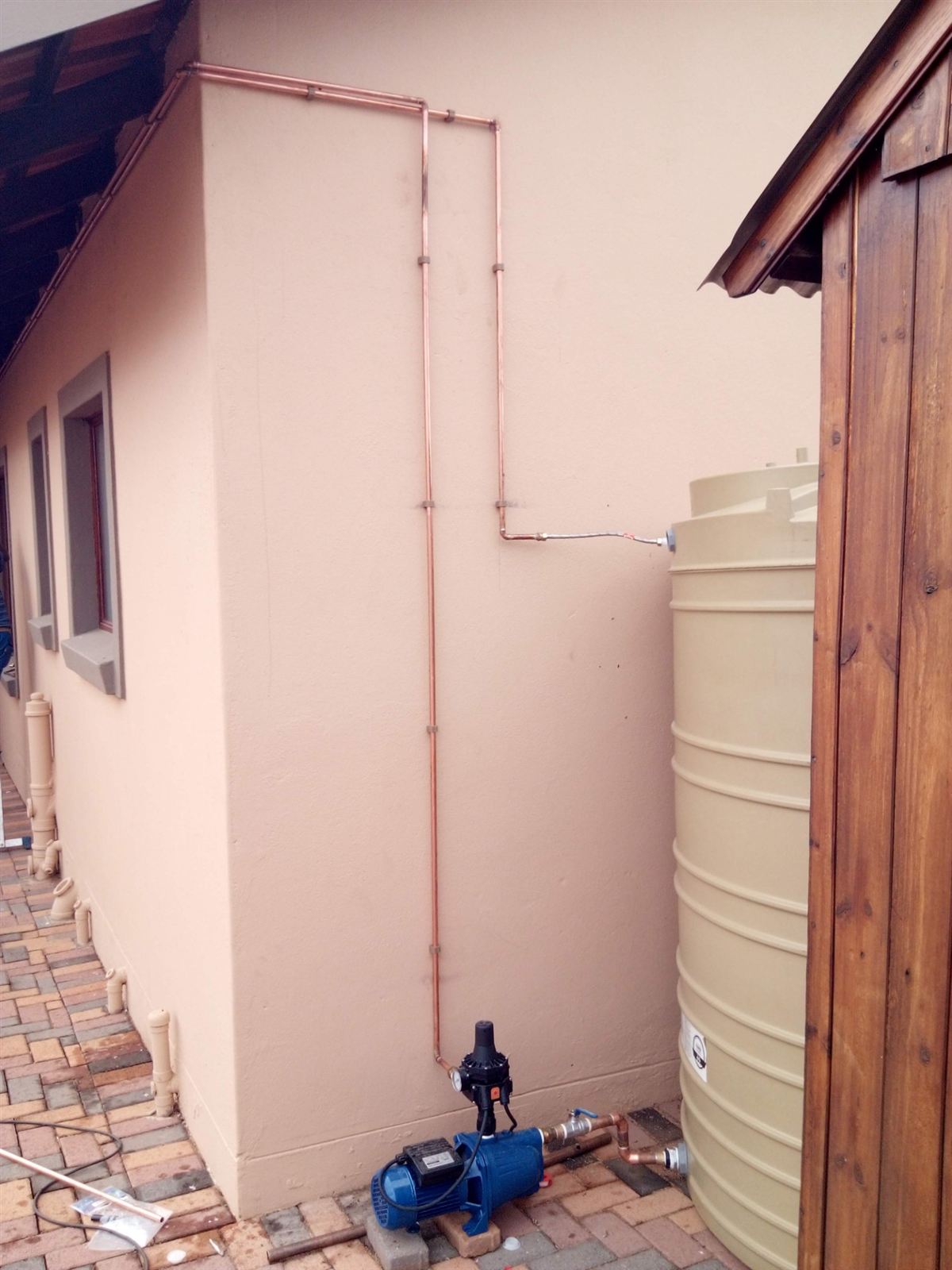 Water tank with booster pump and copper lines up the wall