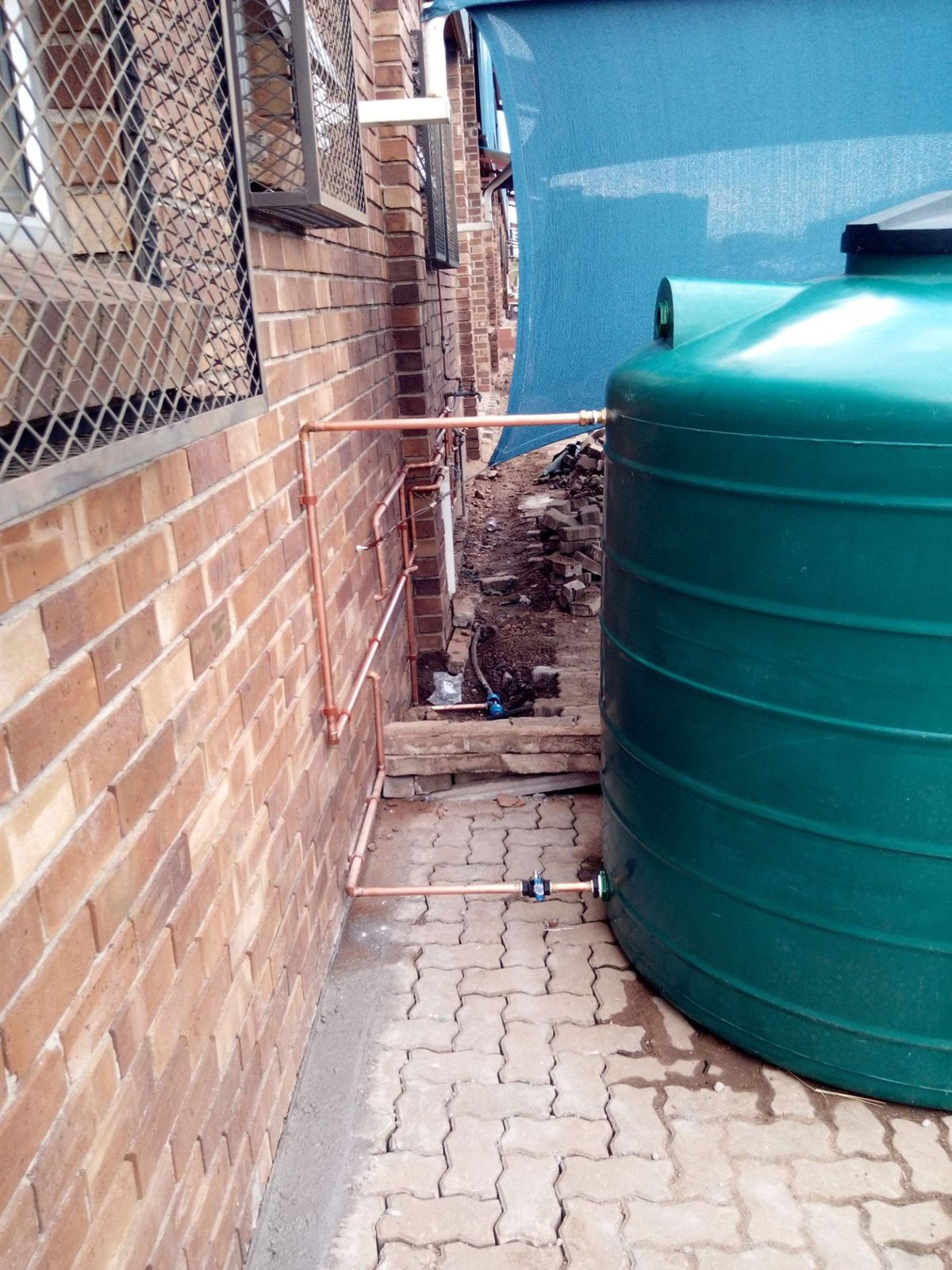 Copper pipework connecting a green water tank to the house