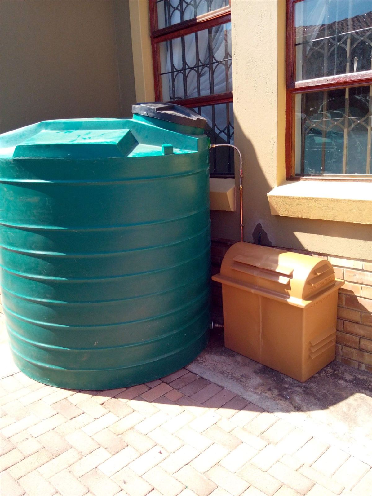 Green water tank with a pump cover beside it